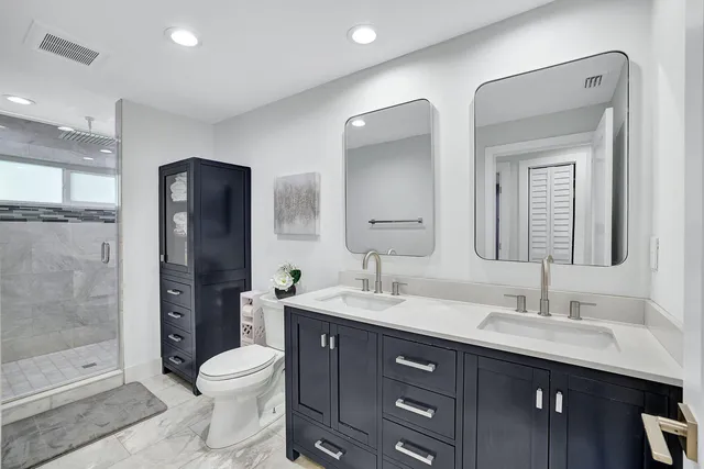a bathroom with a double vanity sink toilet and shower