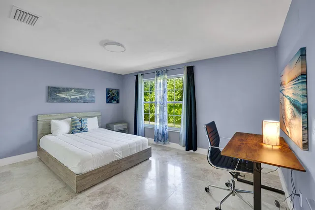 a bedroom with a bed a large window with table and chair