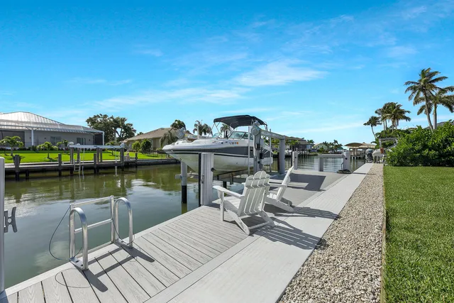 a view of a lake with a table and chairs under an umbrella next to a lake