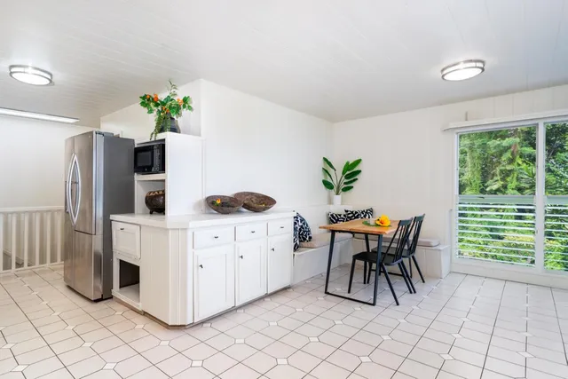 a kitchen with stainless steel appliances a white table chairs and a large window