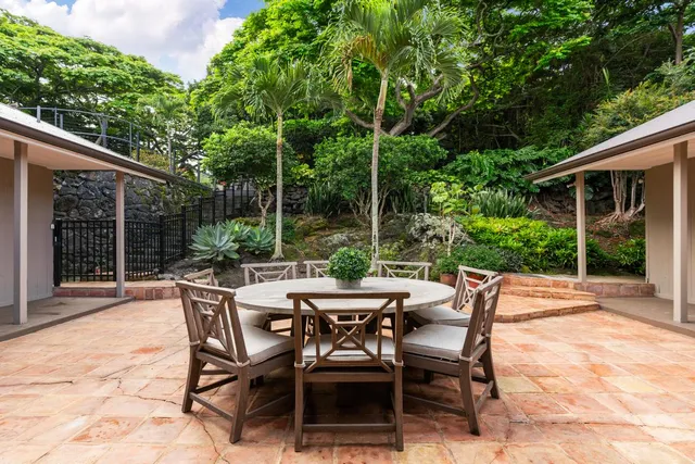 a view of a patio with table and chairs potted plants and floor to ceiling window