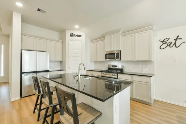 a kitchen with stainless steel appliances granite countertop a sink a stove a microwave a refrigerator and cabinets
