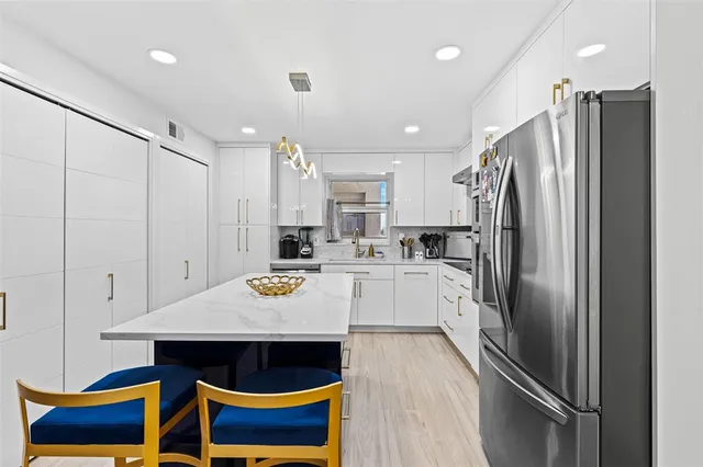 a kitchen with stainless steel appliances a table chairs and refrigerator