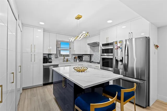 a kitchen with stainless steel appliances granite countertop a refrigerator a sink and a stove