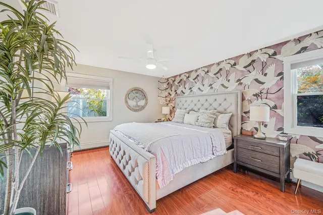 a bedroom with a bed lamp and a large window with wooden floor