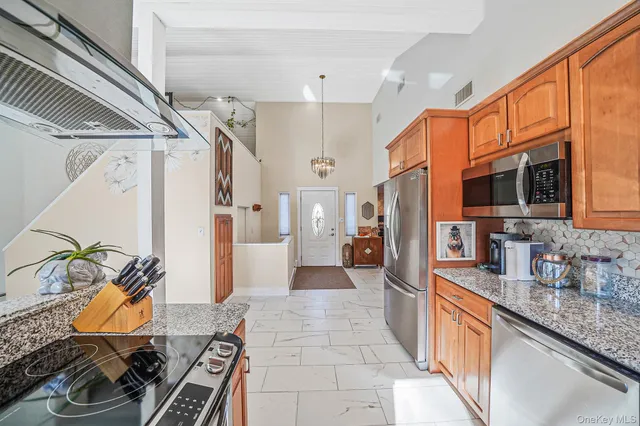 a large white kitchen with stainless steel appliances kitchen island granite countertop a sink and cabinets
