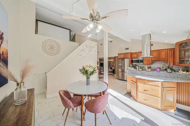 a kitchen with stainless steel appliances kitchen island granite countertop a table chairs in it and wooden floors