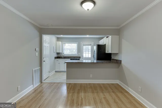 a kitchen with granite countertop a sink dishwasher a refrigerator and cabinets with wooden floor