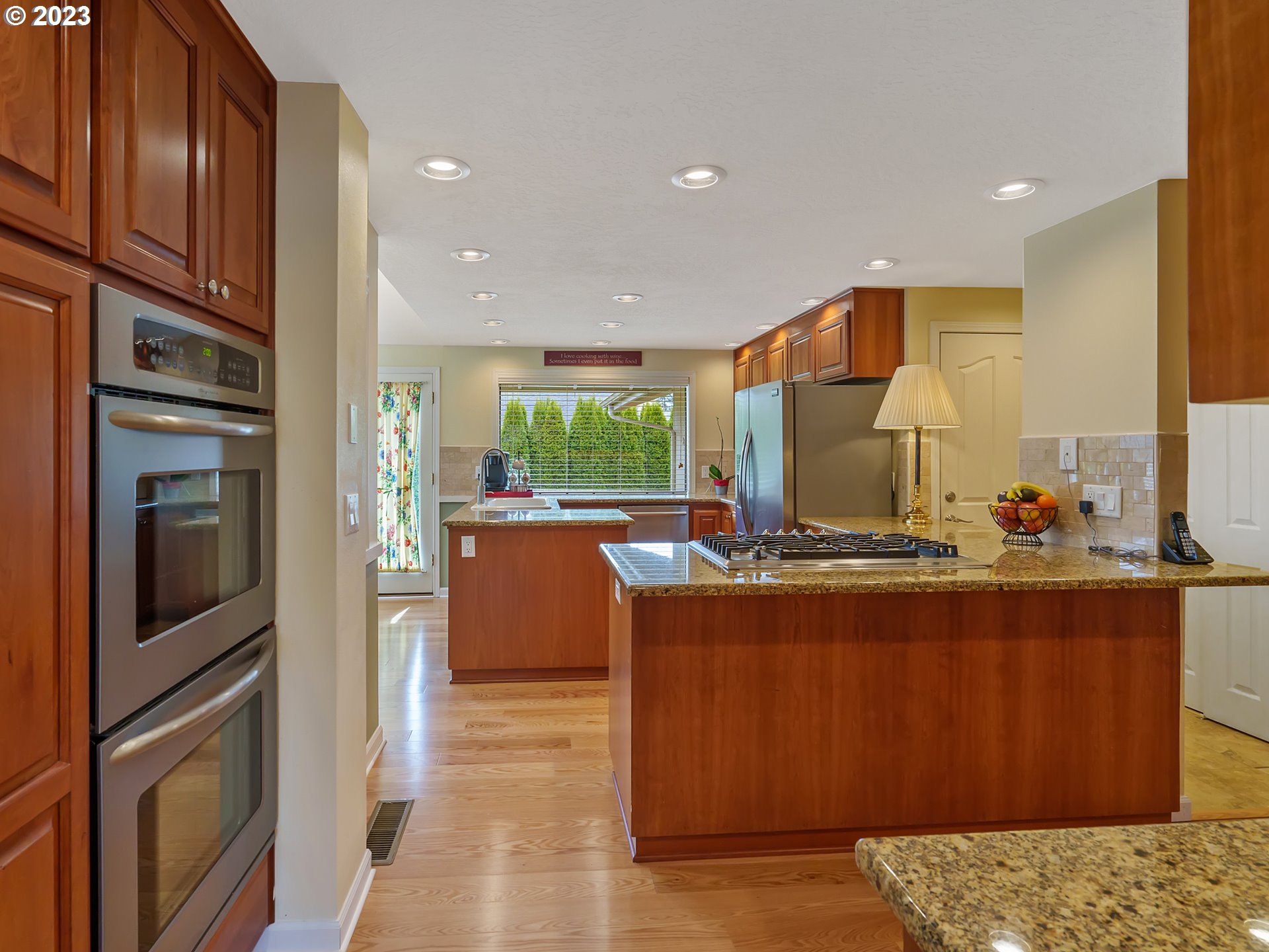 992 Spyglass Drive Eugene, OR 97401 - Photo 7 of 35 a kitchen with stainless steel appliances granite countertop a refrigerator a oven a sink with wooden cabinets and wooden floor