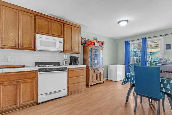 a kitchen with stainless steel appliances granite countertop a stove a refrigerator a dining table and chairs with wooden floor