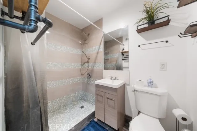 a bathroom with a sink a toilet a mirror and shower