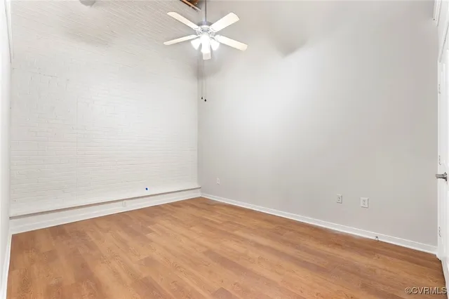 an empty room with a ceiling fan and wooden floor