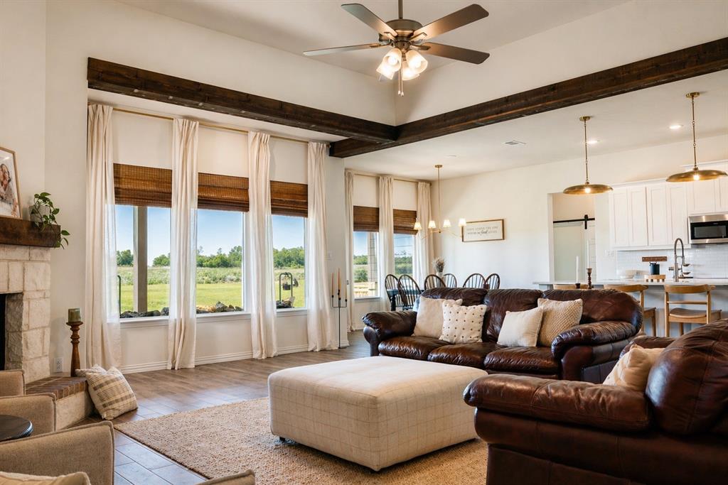 1530 County Road 200 Valley View, TX 76272 - Photo 6 of 34 Spacious living area featuring exposed wood beams, a stone-clad fireplace, and large windows with natural light