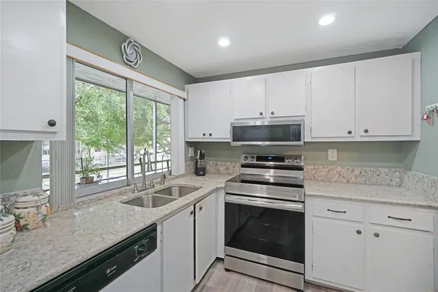 a kitchen with granite countertop a sink stainless steel appliances and cabinets