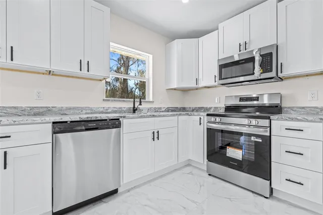 a kitchen with granite countertop white cabinets stainless steel appliances and a sink