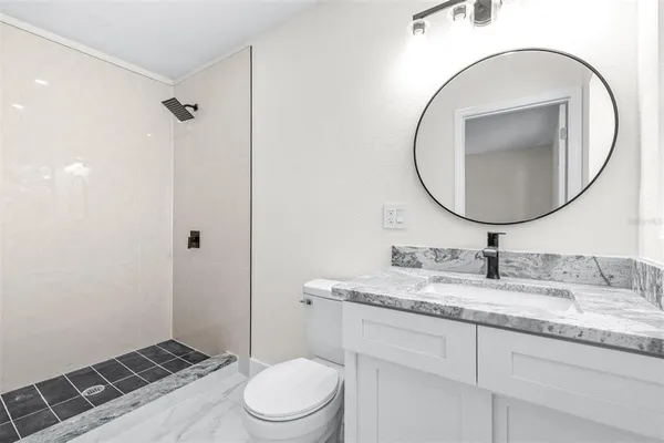 a bathroom with a granite countertop toilet sink and mirror