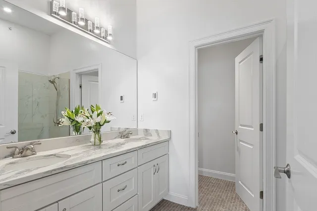 a bathroom with a granite countertop double vanity and a mirror