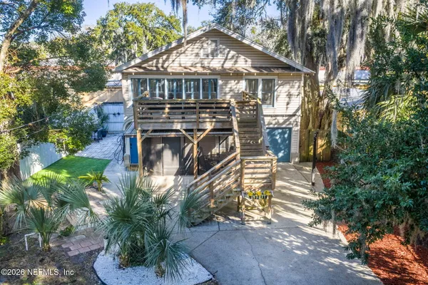 a view of a small yard in front of a house with large trees and plants
