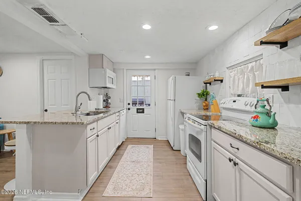 a large kitchen with stainless steel appliances granite countertop lots of counter top space and white cabinets