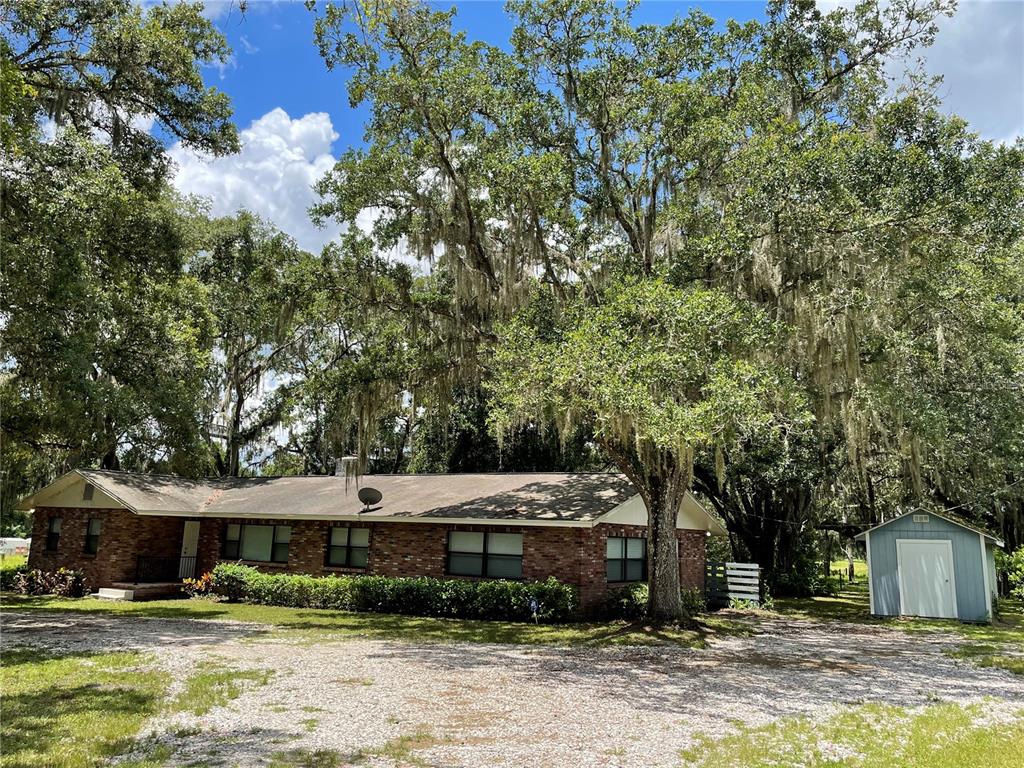 3267 Rackley Road Brooksville, FL 34604 - Photo 2 of 23 a view of a white house next to a yard with plants and trees