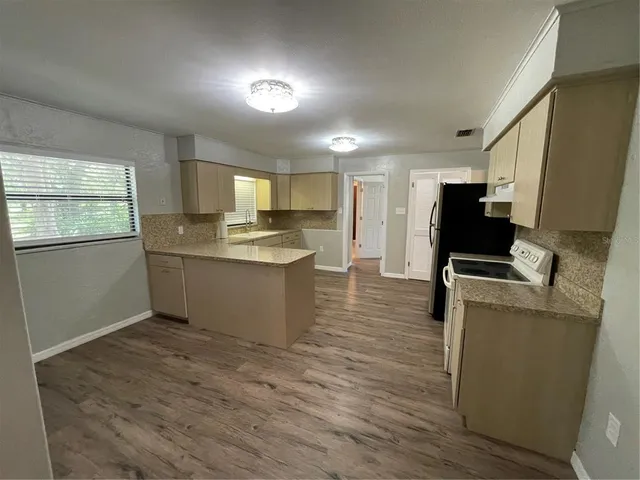 a kitchen with a sink wooden floor and black appliances
