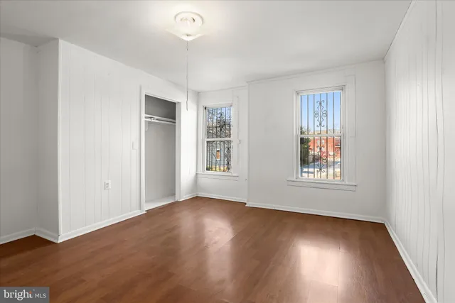an empty room with wooden floor and windows