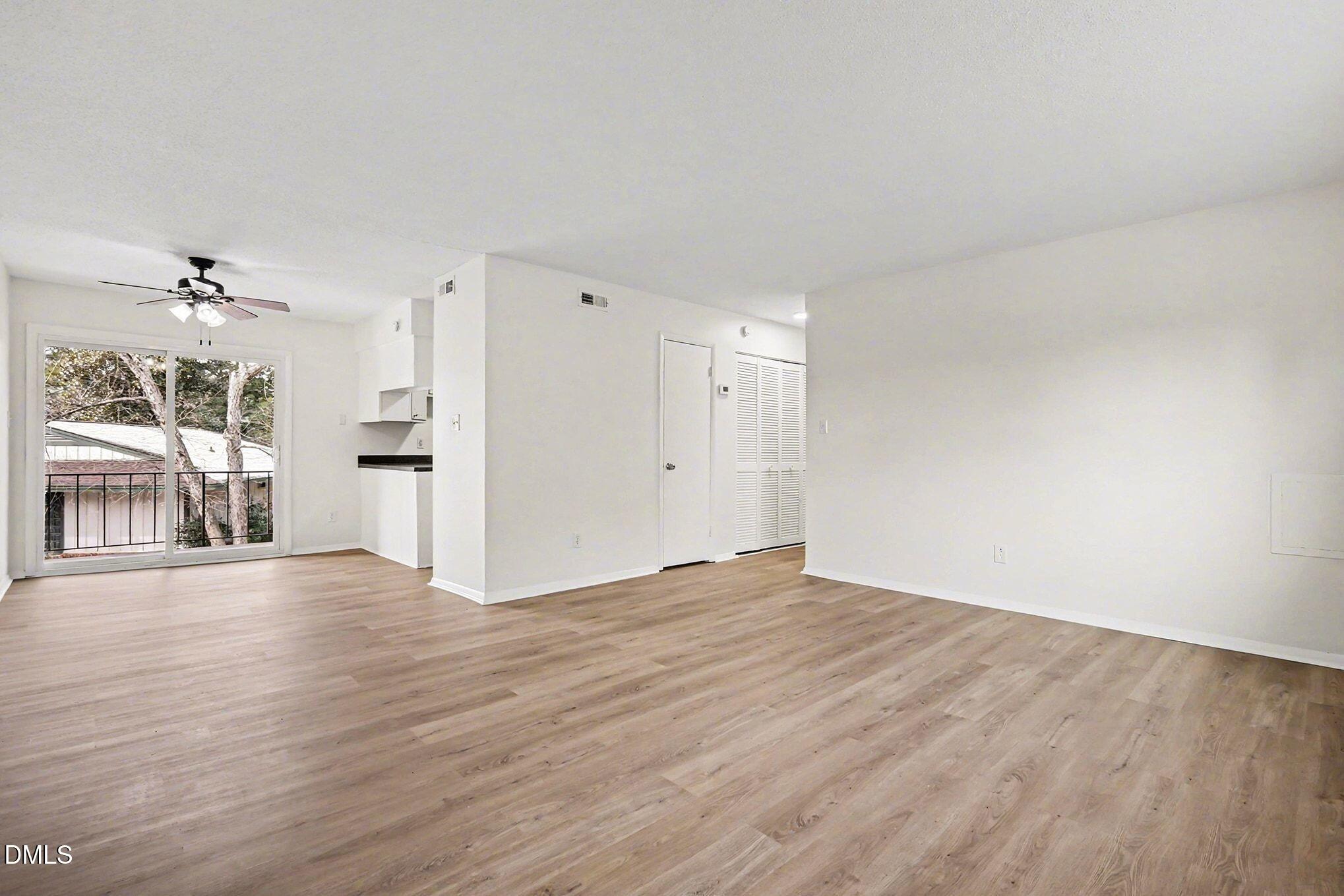 5612 Falls Of Neuse Road, Unit H Raleigh, NC 27609 - Photo 4 of 14 a view of an empty room with wooden floor and a window