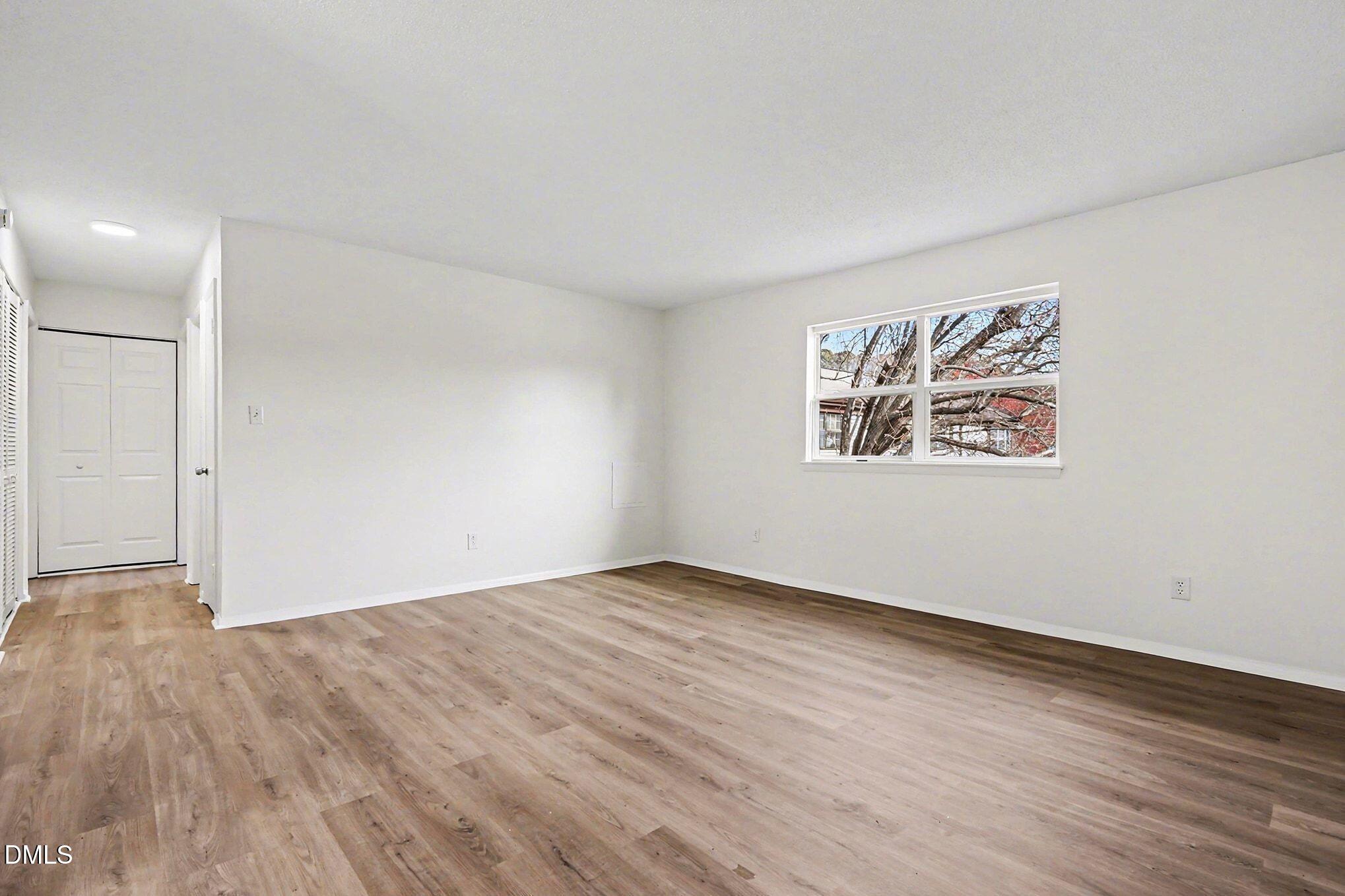 5612 Falls Of Neuse Road, Unit H Raleigh, NC 27609 - Photo 5 of 14 an empty room with wooden floor and windows
