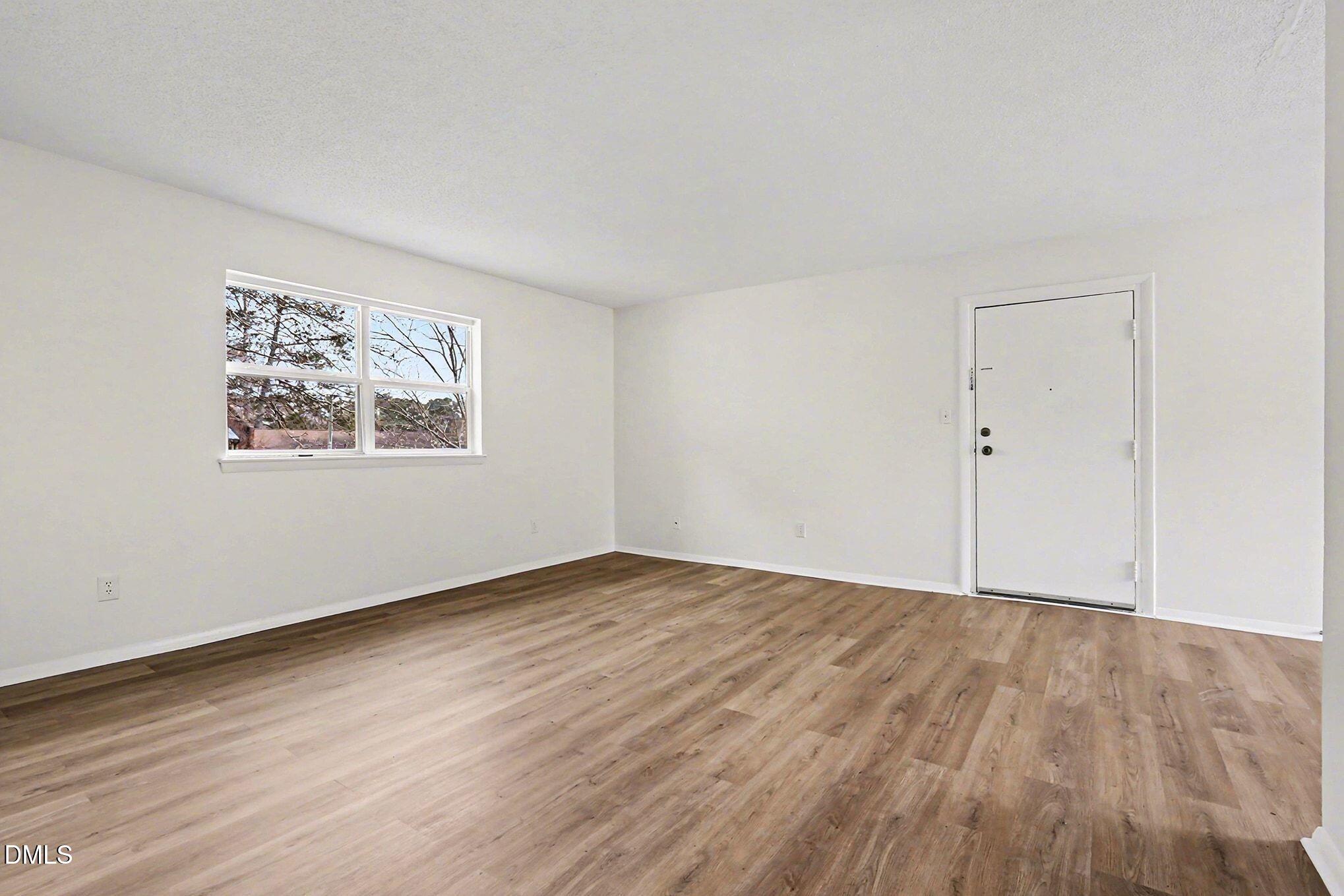 5612 Falls Of Neuse Road, Unit H Raleigh, NC 27609 - Photo 9 of 14 an empty room with wooden floor and windows