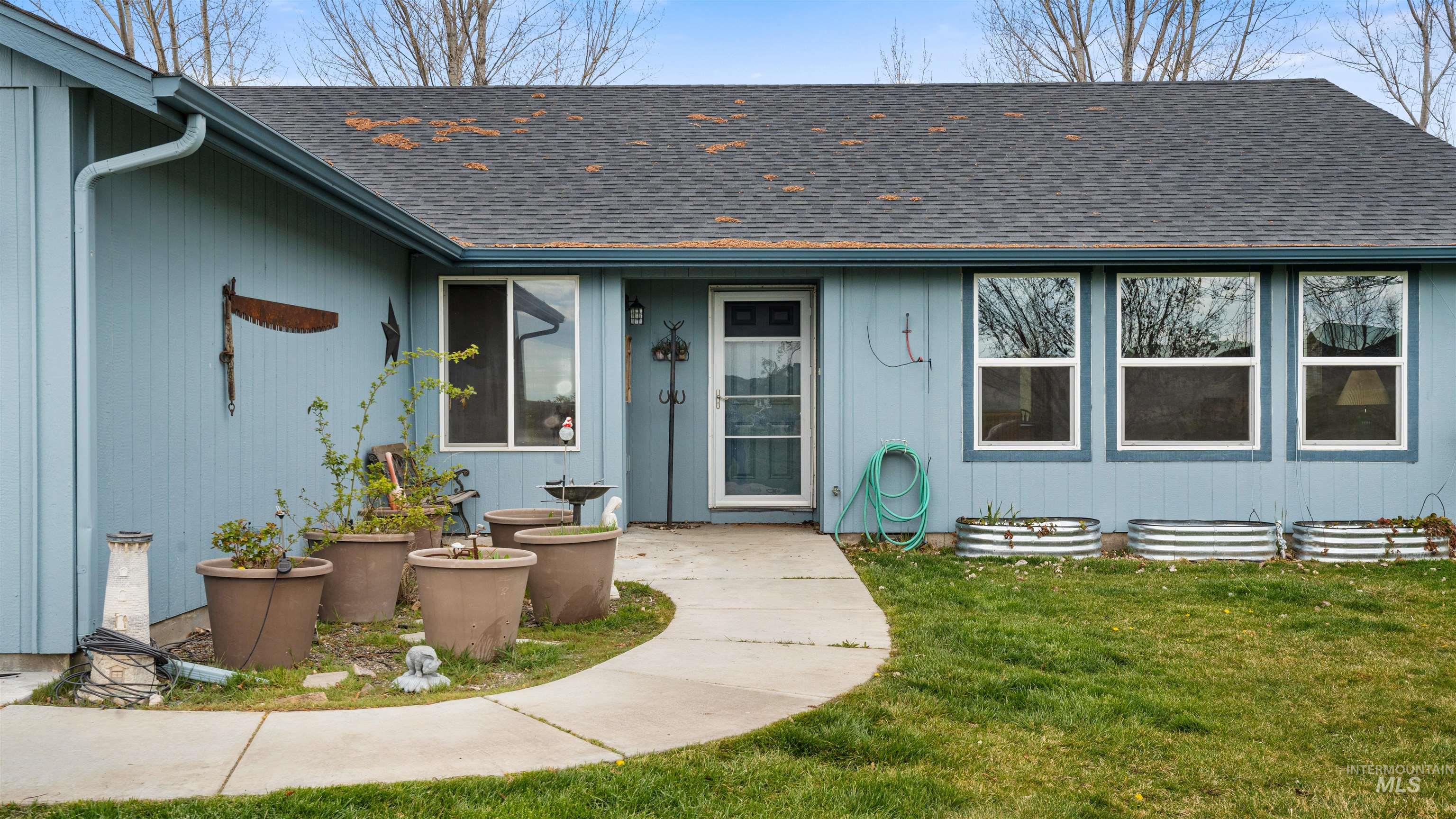 731 Tower Lane Caldwell, ID 83607 - Photo 13 of 38 Property entrance with roof with shingles, a lawn, and a patio