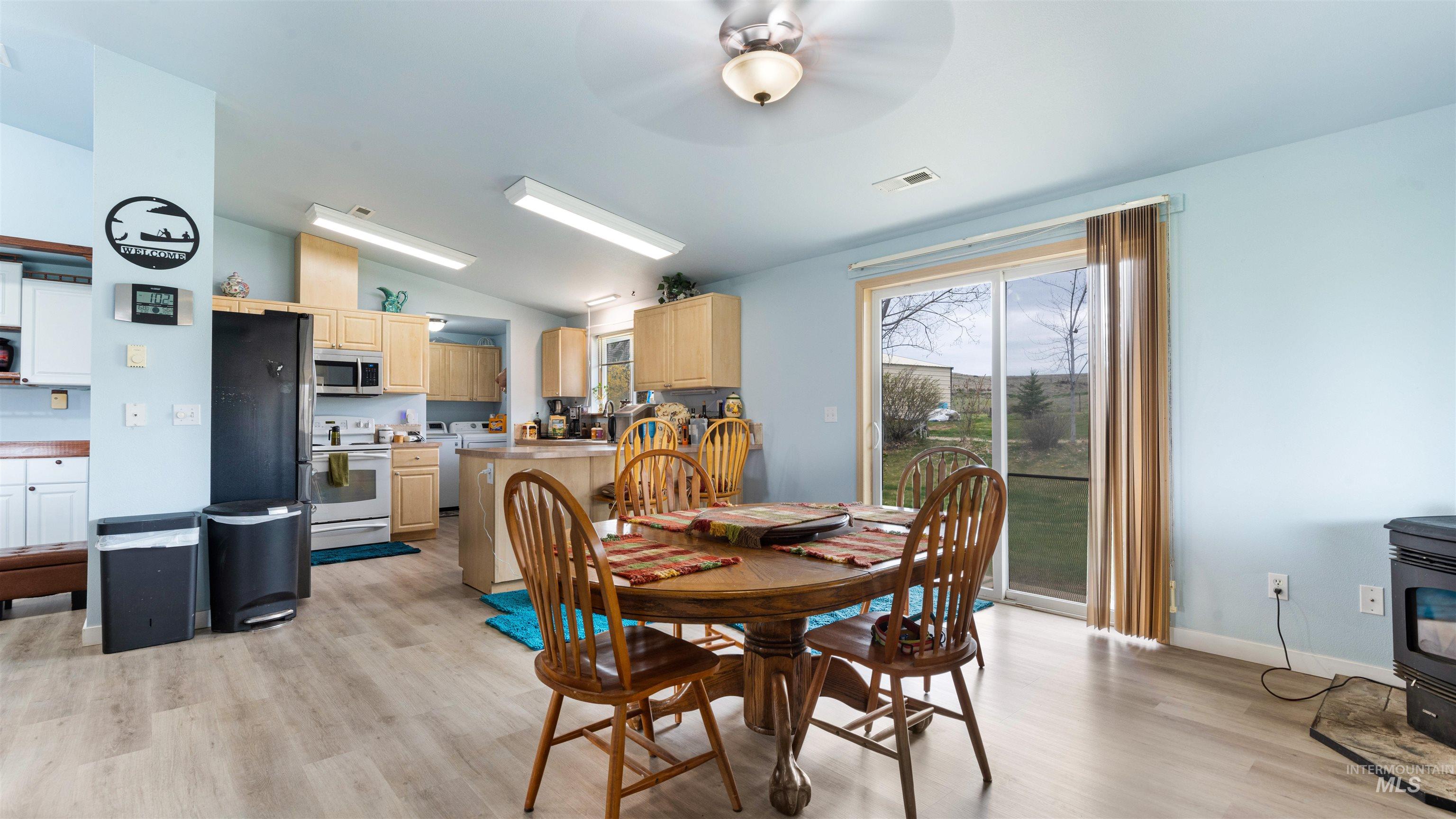 731 Tower Lane Caldwell, ID 83607 - Photo 23 of 38 Dining area featuring lofted ceiling, a wood stove, ceiling fan, and light wood-style flooring