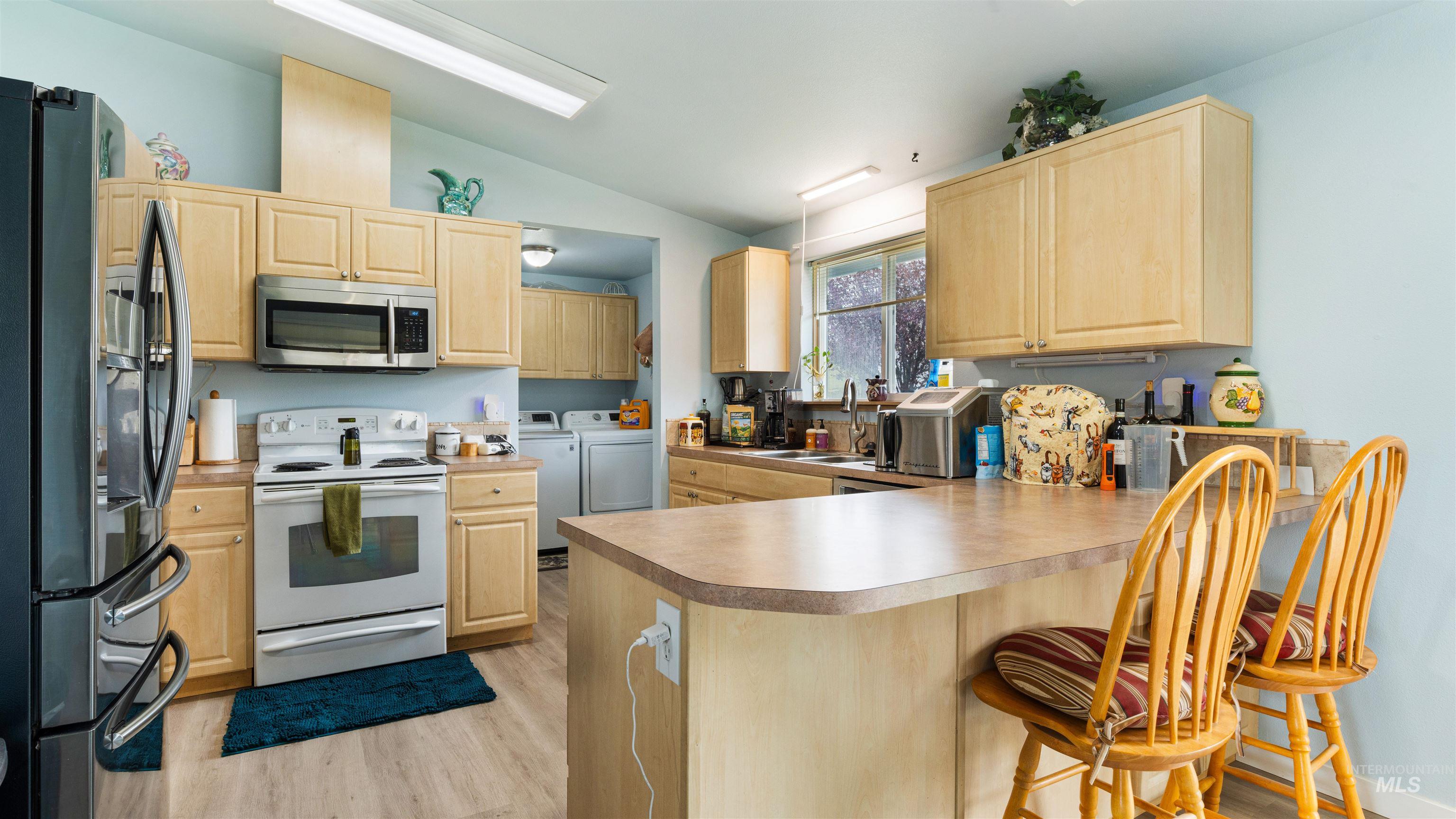 731 Tower Lane Caldwell, ID 83607 - Photo 25 of 38 Kitchen featuring light wood finish cabinetry, stainless steel appliances, a peninsula, lofted ceiling, and separate washer and dryer