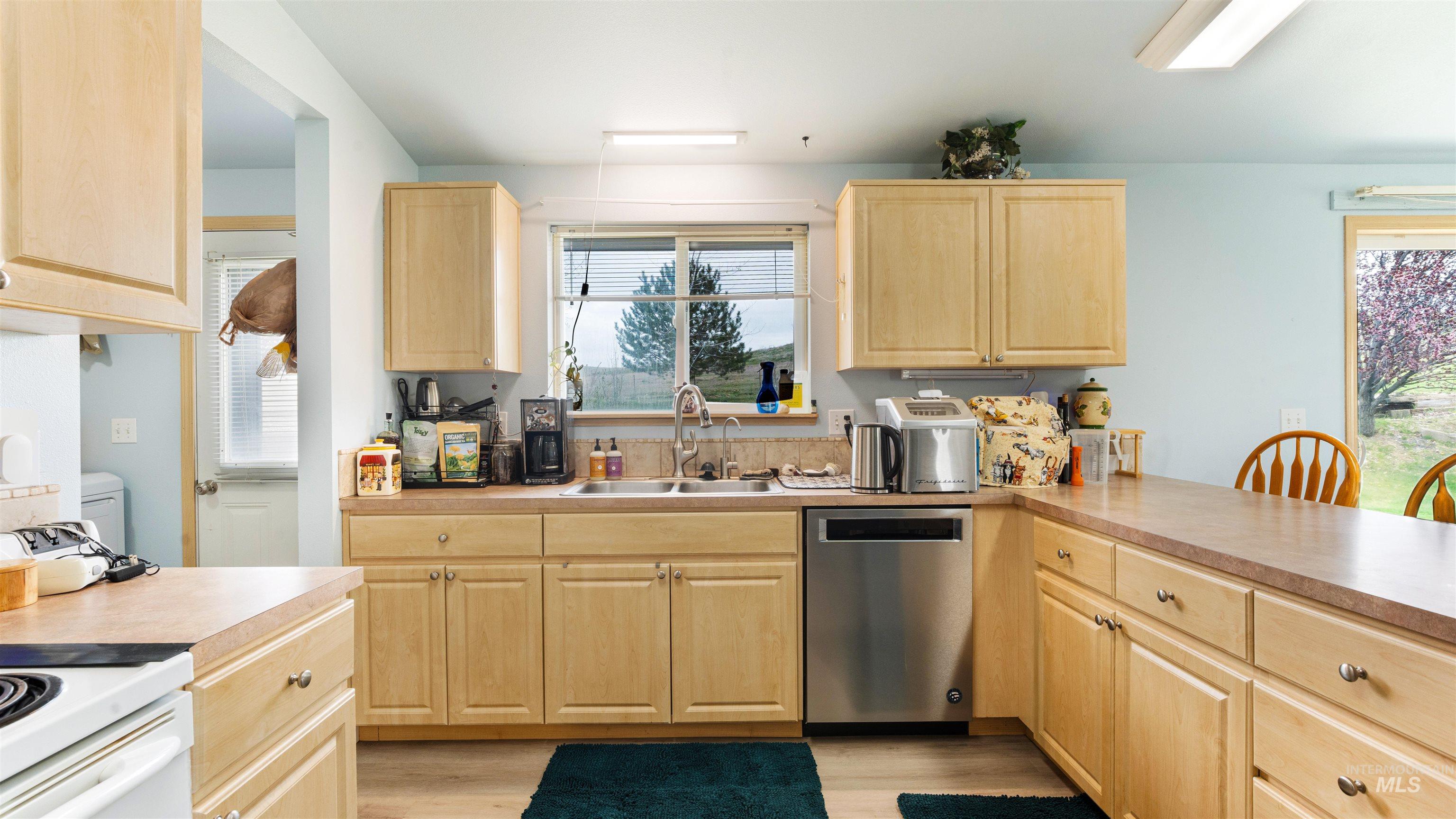 731 Tower Lane Caldwell, ID 83607 - Photo 28 of 38 Kitchen featuring light wood finish cabinets, stainless steel dishwasher, light countertops, light wood-style flooring, and electric range