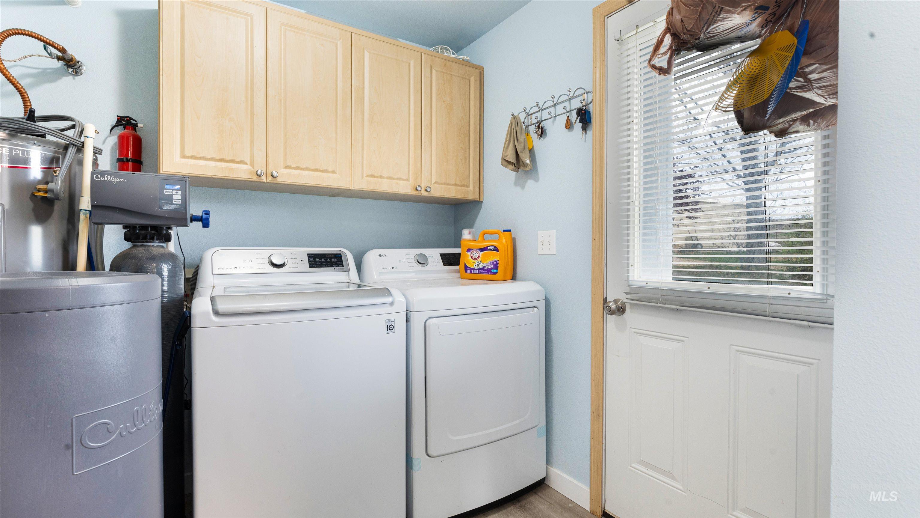 731 Tower Lane Caldwell, ID 83607 - Photo 29 of 38 Laundry area featuring cabinet space, washing machine and clothes dryer, water heater, and light wood finished floors