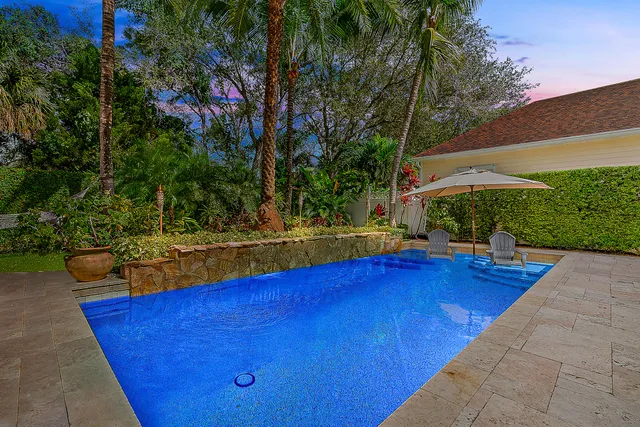 a view of pool with lawn chairs and plants