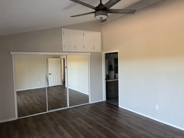 an empty room with wooden floor closet and windows