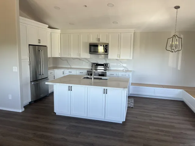 a kitchen with kitchen island granite countertop a sink cabinets and stainless steel appliances