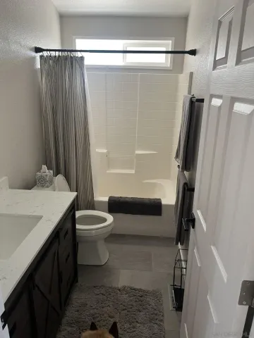 a bathroom with a granite countertop bathtub shower sink vanity and toilet