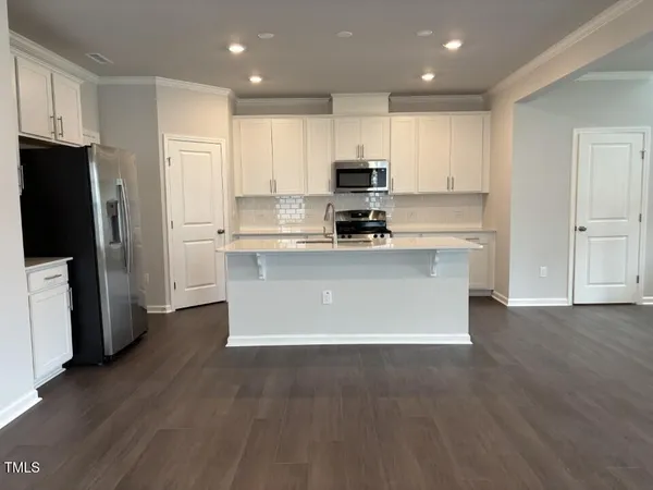 a large kitchen with stainless steel appliances a refrigerator a stove top oven a sink and cabinets