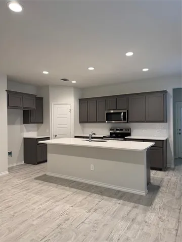 a large white kitchen with kitchen island a sink a stove a center island a stove and a center island