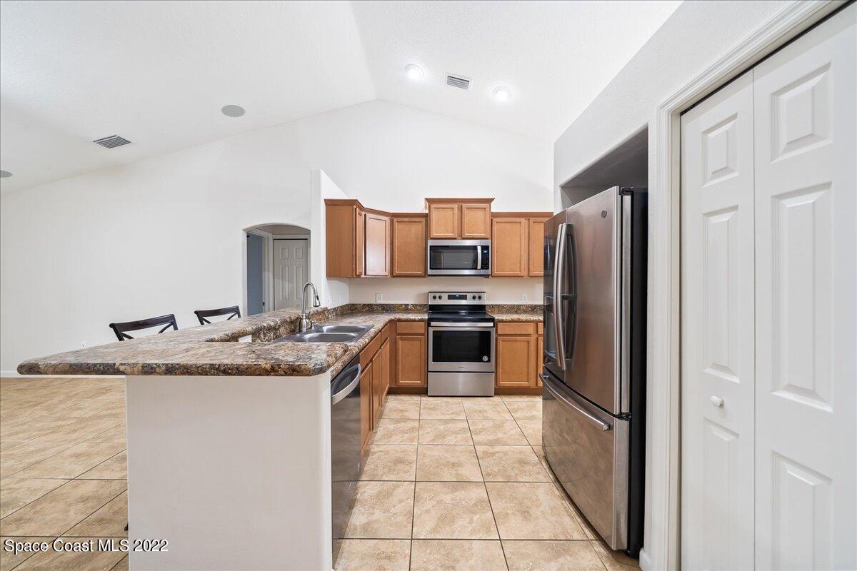 6175 Adina Road Cocoa, FL 32927 - Photo 11 of 29 a kitchen with stainless steel appliances granite countertop a refrigerator a stove and a sink