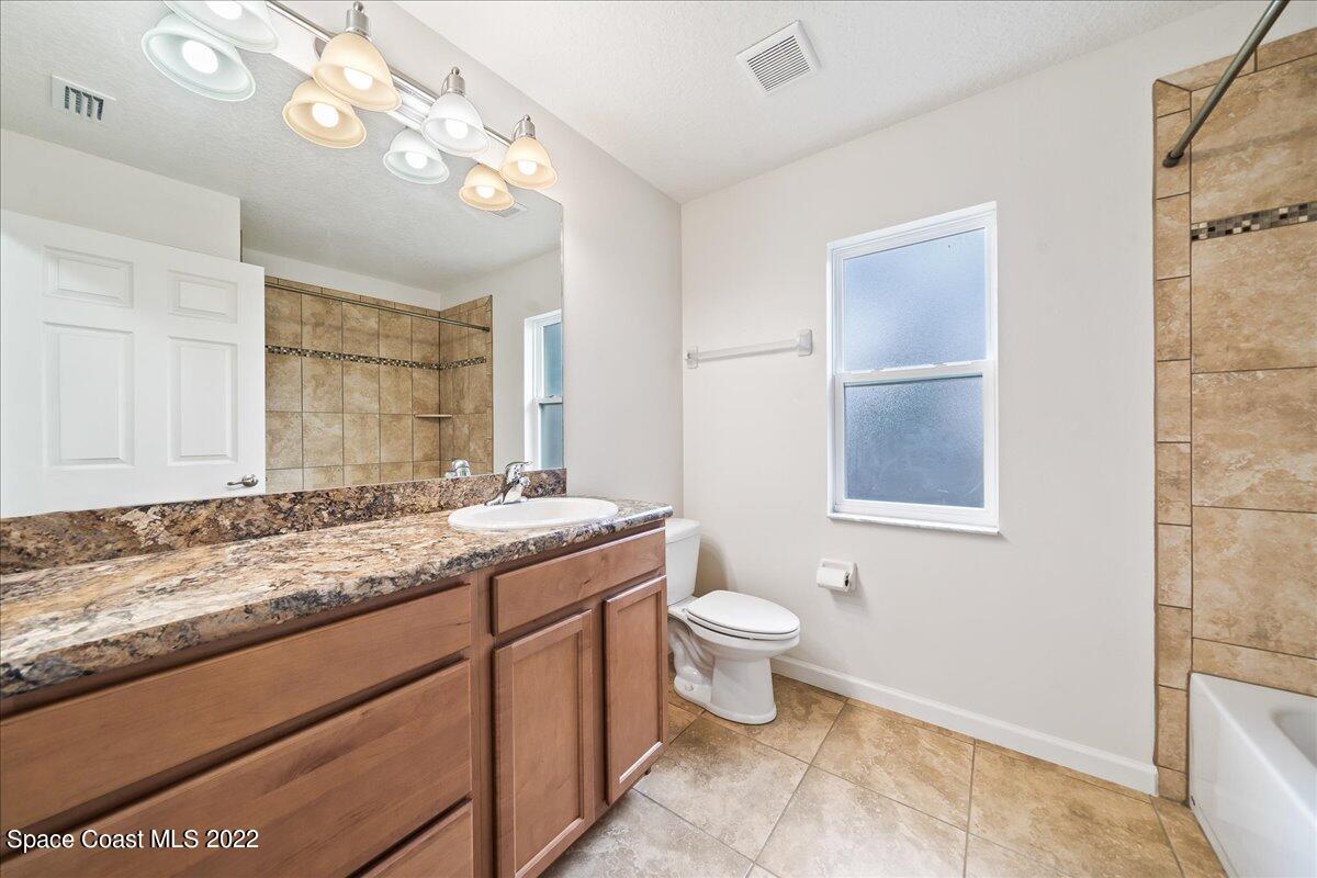 6175 Adina Road Cocoa, FL 32927 - Photo 18 of 29 a bathroom with a granite countertop sink a toilet and a mirror