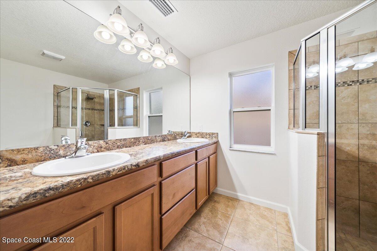 6175 Adina Road Cocoa, FL 32927 - Photo 23 of 29 a bathroom with a granite countertop sink a mirror and a shower