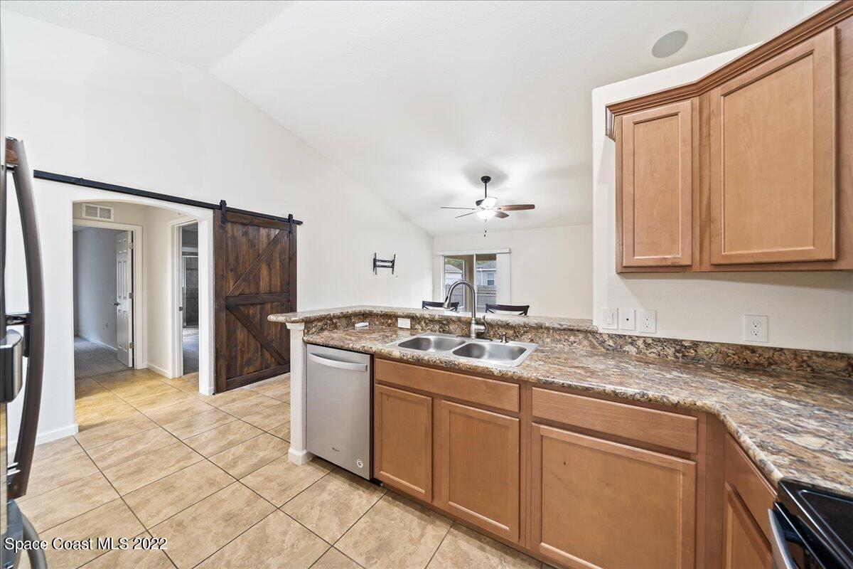 6175 Adina Road Cocoa, FL 32927 - Photo 10 of 29 a kitchen with stainless steel appliances granite countertop a sink stove and refrigerator