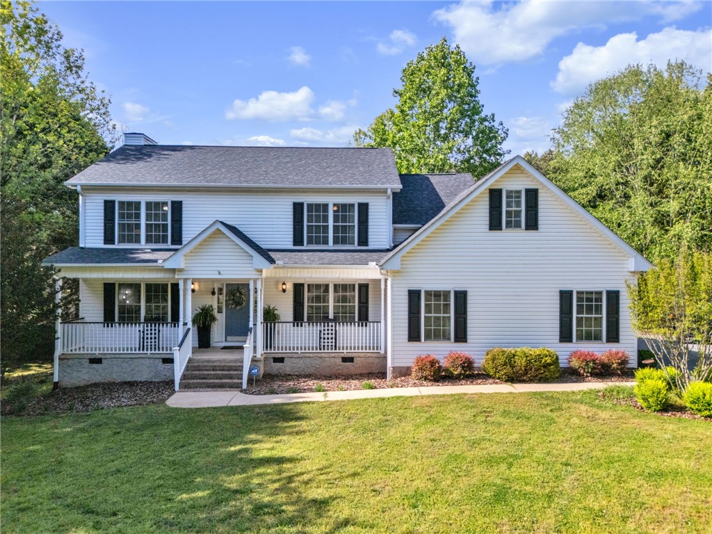 This classic white residence offers a charming front porch and mature landscaping.