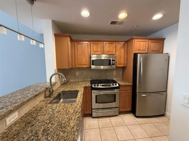 a kitchen with granite countertop a refrigerator and a stove top oven