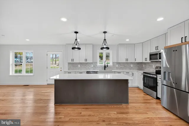 a large kitchen with stainless steel appliances granite countertop a sink stove and refrigerator