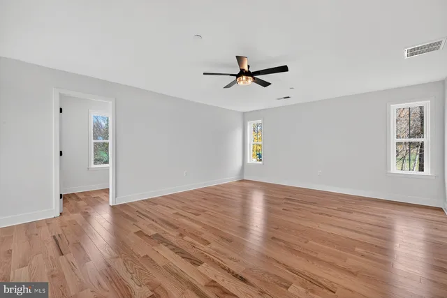a view of empty room with wooden floor and ceiling fan