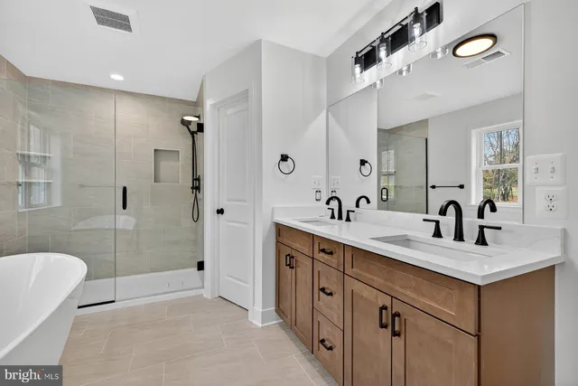 a bathroom with a tub sink double vanity and shower