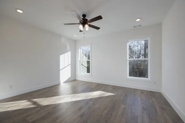a view of an empty room with wooden floor and a window